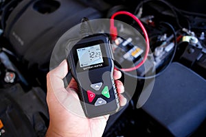 Battery tester in a auto mechanic hand for battery voltage or battery health analysis