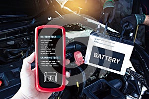 Battery tester in a car mechanic hand for testing battery voltage and battery health