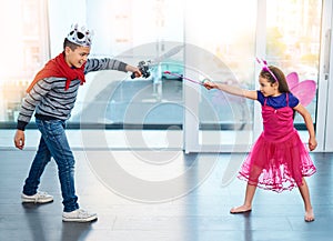 The battle of good vs evil. Full length shit of two young children dressed up as superheroes play fighting at home.