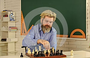 battle of minds. bearded man training for chess competition. chess figures on wooden board. Focused school teacher