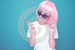Bautiful 90s girl in a whit t-shurt and black glasses with lollipop in a blue room.