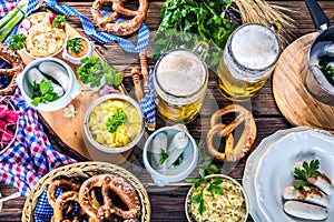Bavarian beer with soft pretzels, wheat and hop on rustic wooden