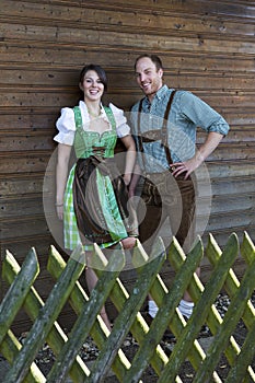 Bavarian couple standing behind a wooden fence