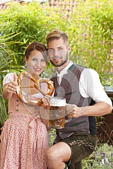 Bavarian couple in traditional costume with beer and brezel