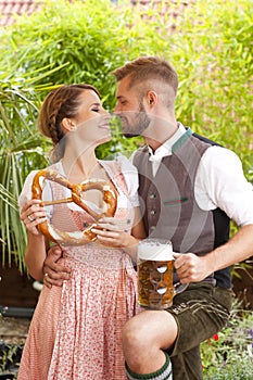 Bavarian couple in traditional costume with beer and brezel