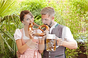 Bavarian couple in traditional costume with beer and brezel