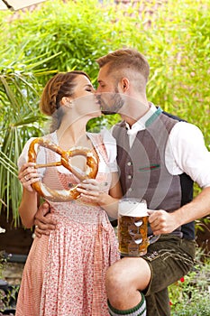 Bavarian couple in traditional costume with beer and brezel