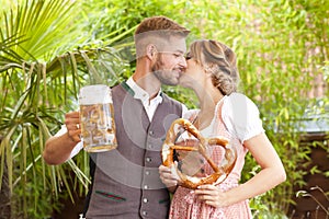 Bavarian couple in traditional costume with beer and brezel