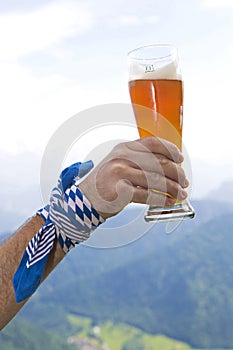 Bavarian holding wheat beer glass in the air