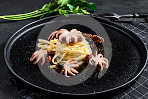 Bavette pasta with baby octopus. Black background. Top view photo