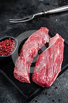 Bavette raw beef meat steak or Sirloin flap on marble board. Black background. Top view