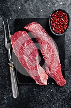 Bavette raw beef meat steak or Sirloin flap on marble board. Black background. Top view