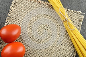 Bavette and tomatoes on a burlap cloth with a dark background.