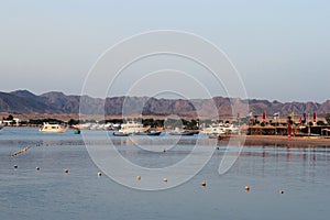 Bay and boats on the water. Boat station on the shore. Low mountains in the distance. Resort on the Red sea coast, Egypt