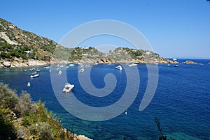 A bay in Giglio Island: the rocky coast and boats off the coast photo