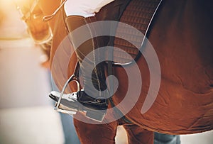 On a Bay horse in the saddle sits a rider, whose foot is dressed in a black boot and rests on a stirrup