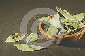 bay leaf on a dark surface/ bay leaf in a wooden bowl on a black stone background. selective focus