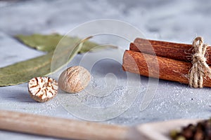 Bay leaf, nutmeg and cinnamon on white textured background, top view, close-up, selective focus.