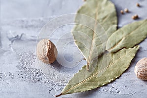 Bay leaf, nutmeg and spices on white textured background, top view, close-up, selective focus.