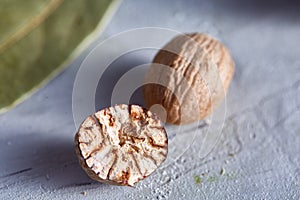 Bay leaf and nutmeg on white textured background, top view, close-up, selective focus.