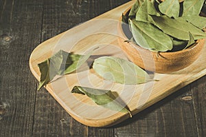 Bay leaf on a tray in a wooden bowl/bay leaf in a wooden plate on a tray, rural style. Top view