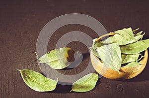 Bay leaf in a wooden bowl/bay leaf in a wooden bowl on a black s