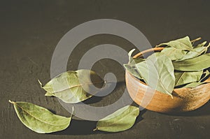 Bay leaf in a wooden bowl/bay leaf in a wooden bowl on a black stone background. selective focus