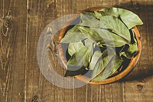 Bay leaf in a wooden bowl/bay leaf in a wooden bowl on a wooden background. Top view
