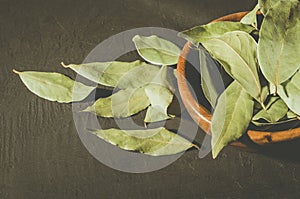 Bay leaf in a wooden bowl on a dark stone surface/bay leaf in a