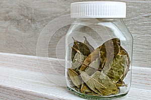 Bay leaves in a jar. Dried flakes of laurel tree.