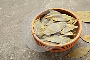 Bay leaves in wooden bawl on a concrete background