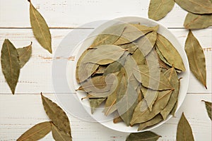 Bay leaves in wooden bawl on white background