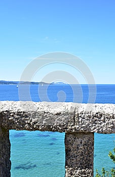 Bay with stone handrail, trees and sailing boats. Rias Baixas, Spain.