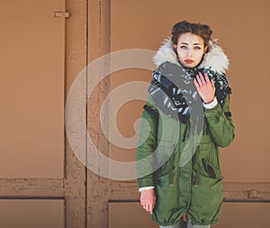 Bbeautiful unusual girl in a green jacket next to the brown door