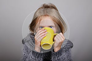 Bblond hair little girl a cup of hot tea in hands. Sick child. Child winter flu health care concept