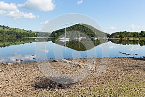 BBQ ashes by beautiful lake on calm idyllic summer morning with cloud reflections