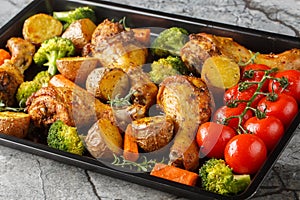 BBQ baked chicken drumsticks with seasonal vegetables and rosemary close-up on a baking sheet. Horizontal