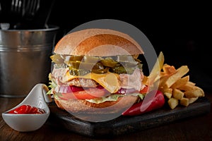 Bbq beef cheeseburger with pickled Jalapeno peppers, cheese and vegetables with French fries