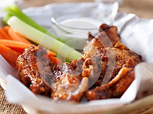 Bbq buffalo chicken wings in basket, with ranch dip, carrot and celery sticks