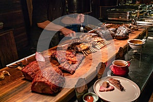 BBQ chef cutting huge grilled lamb ribs at buffet restaurant