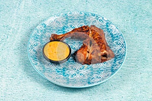 bbq chicken leg piece served in a dish isolated on background side view