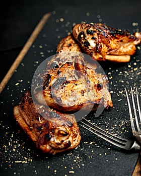 BBQ chicken thighs on a black cutting board. Soft focus. Vertical shot