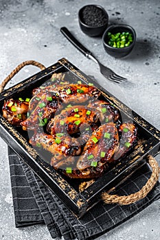 BBQ Chicken wings in Teriyaki sauce with black sesame in a tray. Gray background. Top view