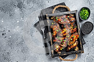 BBQ Chicken wings in Teriyaki sauce with black sesame in a tray. Gray background. Top view. Copy space