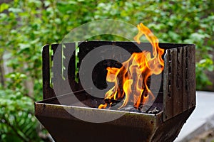 BBQ grill flame burning fire, barbecue outdoors for cooking food in garden. Big and tall grill flames on barbecue, green