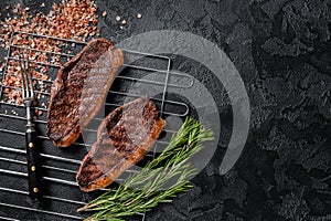 BBQ Grilled cap rump or Top sirloin beef steak, fried meat on grill. Black background. Top view. Copy space