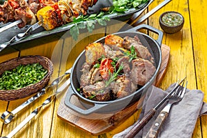 Bbq grilled meat - pork, chicken and vegetable on cast iron pan. Grilled skewers on yellow wooden background. Top view