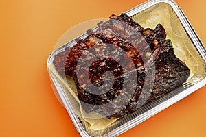 BBQ grilled ribs in a metal tray for delivery. Take out concept, eating at home. In foil delivery box, food take away