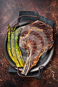 BBQ Grilled Tomahawk or Cowboy with bone beef steak, roasted asparagus. Wooden background. Top view