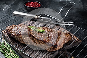 BBQ grilled tri tip beef steak on a grill. Black background. Top view